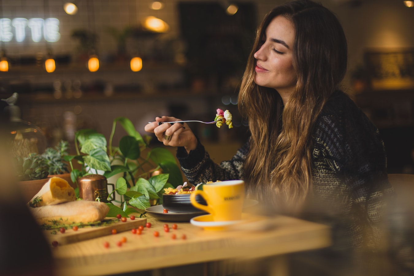 Frau sitzt im Café und isst einen Salat